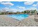 Community pool with a paved pool deck and lounge chairs surrounded by green space and blue skies at 10533 Belfry Cir, Orlando, FL 32832