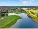 An aerial view of a lush golf course with a pond and a luxurious clubhouse in a beautiful residential community at 10533 Belfry Cir, Orlando, FL 32832