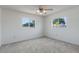 Carpeted bedroom features neutral walls, ceiling fan, and two windows offering a bright, airy space at 10980 Sw 62Nd Ave, Ocala, FL 34476