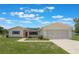 Charming single-story home featuring a well-maintained lawn, red front door, and two-car garage at 10980 Sw 62Nd Ave, Ocala, FL 34476