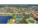 An aerial view shows a community's tennis courts, a pool, landscaping, and houses near a lake at 11556 Via Lucerna Cir, Windermere, FL 34786