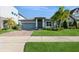 Beautiful home showcasing a well-maintained lawn, brick driveway, and complemented by mature palm trees and blue sky at 1757 Standing Rock Cir, Oakland, FL 34787