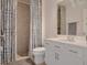 Bathroom featuring a shower with blue-patterned curtains, white vanity, toilet and mirror at 178 Aria Way, Davenport, FL 33837