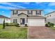 Charming two-story home featuring a brick driveway, attached garage, and well-maintained landscaping at 178 Aria Way, Davenport, FL 33837