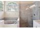Bright bathroom with a soaking tub, a glass-enclosed shower, and a arched window at 220 Wimbledon Cir, Lake Mary, FL 32746