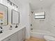 Modern bathroom featuring double sinks, marble tile, and a shower-tub combo at 2205 Pine Island Dr, New Smyrna Beach, FL 32168