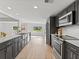 Modern kitchen with stainless steel appliances, gray cabinetry, and a view to the front yard at 2205 Pine Island Dr, New Smyrna Beach, FL 32168