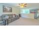 Open-concept living room with neutral carpet and a modern gray sofa, adjacent to a staircase at 2783 Red Horse Dr, Kissimmee, FL 34744