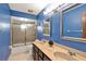 Bright blue bathroom featuring a dual sink vanity, modern lighting, a toilet, and a glass-enclosed shower at 28136 Tammi Dr, Tavares, FL 32778