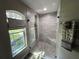 Bathroom including a walk-in shower featuring neutral tiling, a glass door, and a window for natural light at 3064 S Us Highway 41, Dunnellon, FL 34432