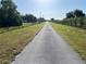 Long paved driveway flanked by green grass and fencing, leading to a private estate at 3064 S Us Highway 41, Dunnellon, FL 34432