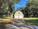 Two car garage with second story and private driveway surrounded by large trees and green lawn at 3064 S Us Highway 41, Dunnellon, FL 34432