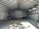 Interior of metal outbuilding with overhead door, concrete floor, and workspace at 3064 S Us Highway 41, Dunnellon, FL 34432