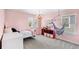 Playful pink bedroom with a swinging chair, storage cubbies, and ample natural light at 3294 Hanging Tide St, Winter Garden, FL 34787
