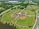 Aerial view showcasing multiple baseball fields with well-maintained green grass, lighting, and connected by pathways in a community at 3945 Angola Ln, Sanford, FL 32771