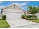 Inviting home featuring a two-car garage, lush green lawn, and tidy landscaping enhancing its appeal at 3945 Angola Ln, Sanford, FL 32771