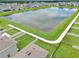 Aerial view of a pond surrounded by green space with a walking path and houses at 3945 Angola Ln, Sanford, FL 32771