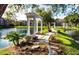 Scenic pond view featuring lush landscaping, stone pathways, and elegant white gazebos at 4225 Thornbriar Ln # 305, Orlando, FL 32822