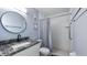 Clean bathroom featuring a granite vanity top, modern round mirror, and a tub shower with grab bars at 4465 Ring Neck Rd # C, Orlando, FL 32808