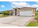 Charming one-story home showcasing a well-maintained lawn, attractive landscaping, and a brick-paved driveway at 5113 Sage Way, Kissimmee, FL 34758