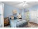 Cozy bedroom with blue walls, wood-look floors, a ceiling fan, a bed with decorative pillows, and closet doors at 5300 S Atlantic Ave # 16-505, New Smyrna Beach, FL 32169