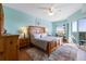 Spacious main bedroom with blue walls, wood furniture, a ceiling fan, rug, and a sliding glass door to the balcony at 5300 S Atlantic Ave # 16-505, New Smyrna Beach, FL 32169