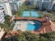Aerial view of a community pool, clubhouse, and tennis courts surrounded by palm trees and buildings at 5300 S Atlantic Ave # 16-505, New Smyrna Beach, FL 32169
