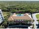 Aerial view of a community pool and recreation building surrounded by lush greenery and a wooden fence at 5300 S Atlantic Ave # 16-505, New Smyrna Beach, FL 32169