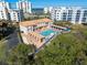 Aerial view of a shared pool area with lounge chairs and shaded seating surrounded by tropical greenery and buildings at 5300 S Atlantic Ave # 16-505, New Smyrna Beach, FL 32169