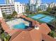 Aerial view of a community pool, tennis courts, and patio area with lounge chairs and shaded seating at 5300 S Atlantic Ave # 16-505, New Smyrna Beach, FL 32169
