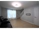 Living room with tile floor, a black leather couch, a window with white curtains, and view of the stairway and front door at 613 Casa Park Court B N Ct # B, Winter Springs, FL 32708