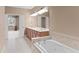 Bathroom with a large soaking tub and a doorway to a bedroom with an open window at 8539 Via Bella Notte, Orlando, FL 32836