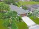 Aerial view of home featuring lush tropical landscaping and a brown two car garage at 9 Abbey Ct, Haines City, FL 33844
