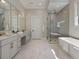 Bright bathroom featuring double vanity, soaking tub, glass shower, and marble floors at 9155 Sheen Sound St, Orlando, FL 32836