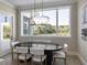 Dining area with black table, six chairs, stylish light fixture, and a large window at 9155 Sheen Sound St, Orlando, FL 32836