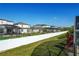 Well-manicured backyard with green grass and a white fence with screened in pools in the background at 1175 Seasons Blvd, Kissimmee, FL 34746
