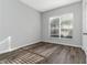 A bedroom with wood floors, a window with blinds, light shining through, and a white door at 1175 Seasons Blvd, Kissimmee, FL 34746