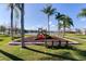 Community playground with slide and benches near a pond surrounded by palm trees and blue skies at 1175 Seasons Blvd, Kissimmee, FL 34746