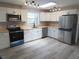Bright kitchen with white cabinets, stainless steel appliances, track lighting, and wood-look flooring at 131 Lake Charles Rd, Deland, FL 32724
