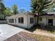 A house's exterior shows a sunroom extension with multiple windows, a concrete patio, and is surrounded by lush trees at 1329 Se 36Th Ave, Ocala, FL 34471