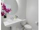 Elegant powder room with a pedestal sink, round mirror, and decorative floral arrangement at 13748 Werrington Dr, Winter Garden, FL 34787