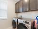 Functional laundry room equipped with modern washer and dryer units and upper cabinets at 13748 Werrington Dr, Winter Garden, FL 34787