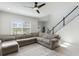 Bright living room with a large gray sectional sofa and staircase with black railing at 13748 Werrington Dr, Winter Garden, FL 34787