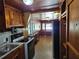 A galley kitchen with wood paneling and cabinetry, with white appliances and view to breakfast nook at 1424 Lake Shore Dr, Casselberry, FL 32707