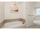 Elegant bathroom featuring chandelier, bathtub with tile accents, and pedestal sink at 1742 Barcelona Way, Winter Park, FL 32789
