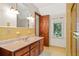 Bathroom with yellow tile, wood cabinet vanity, and a large framed mirror above at 1742 Barcelona Way, Winter Park, FL 32789