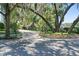 Home exterior with mature trees shading the property, complemented by a stone wall and paved driveway at 1742 Barcelona Way, Winter Park, FL 32789