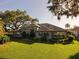 Large backyard with lush green lawn, mature trees, and a view of the home's exterior at 1802 Hartford Path, The Villages, FL 32162