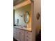 Charming bathroom with marble countertop, gold fixtures, decorative mirror, and neutral wall color at 1802 Hartford Path, The Villages, FL 32162