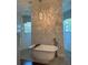 Elegant bathroom featuring a freestanding tub, decorative tile wall, and stylish lighting fixture at 1802 Hartford Path, The Villages, FL 32162